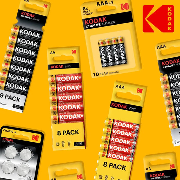 Multiple Kodak AAA and AA alkaline batteries in retail packaging arranged on a bright yellow background, with a large Kodak logo in the upper right.