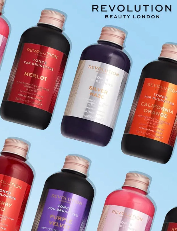 A collage of Revolution Beauty London tone-up serums in dark bottles with rose gold caps, arranged diagonally on a light blue background. Visible products include Merlot, Silver Raze, California Orange, Berry, Purple Velvet, and Rose Velvet.